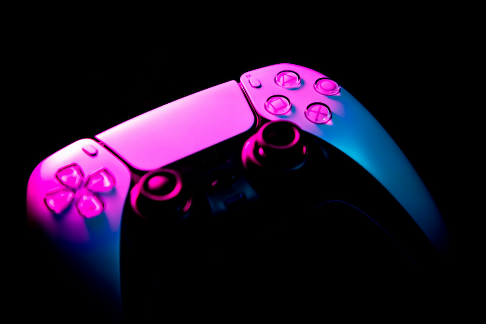 A PlayStation controller lit in pink and blue neon light